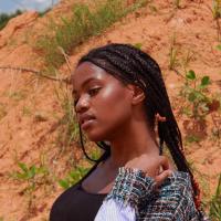 Girl with braids standing in front of sand dune.