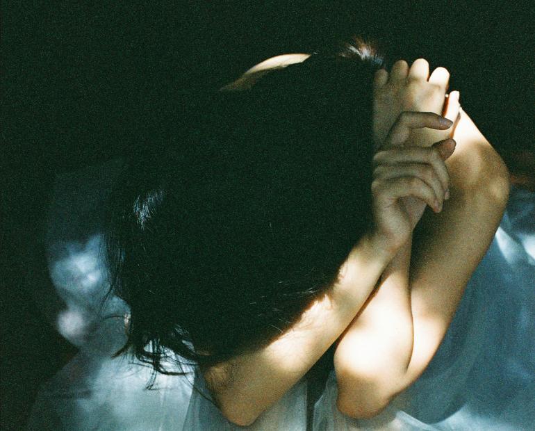 young girl covering her face with elbows in blue dress