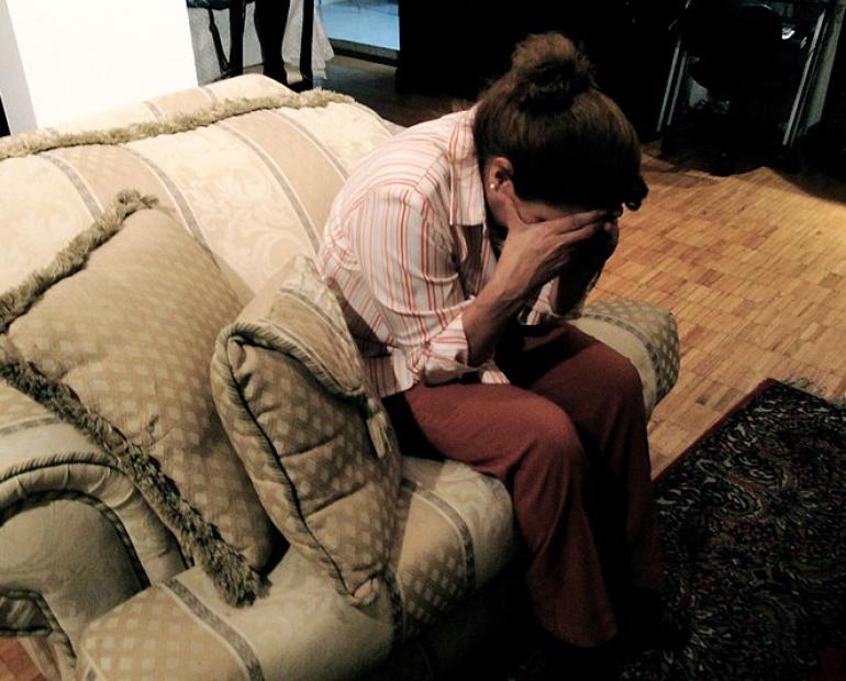 Woman, sitting with her head bowed down