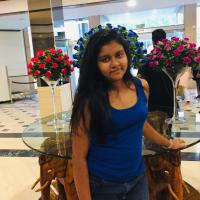 A girl standing in front of some vases of roses