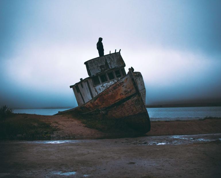 A man stands on a ship at the beach.