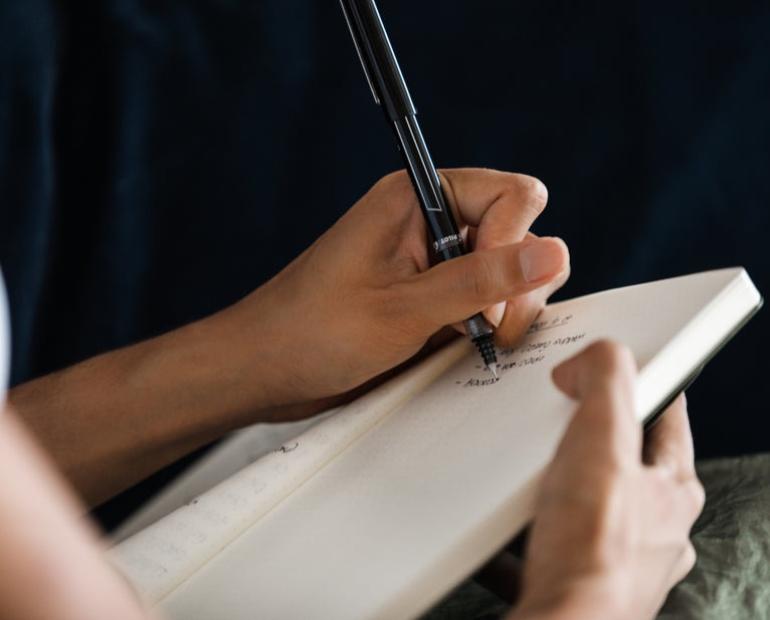 Someone writing in a journal on the couch 