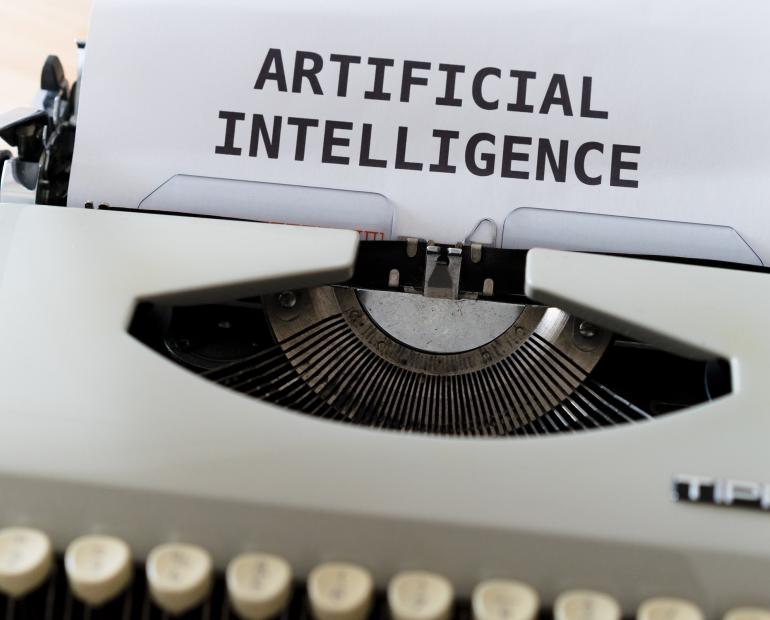 Typewriter with a piece of paper that says "Artificial Intelligence"