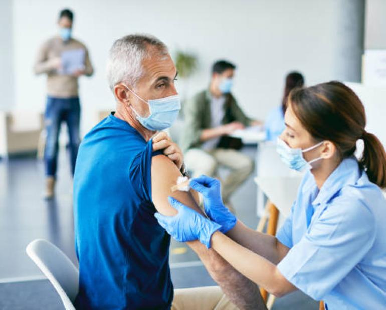 A mature man about to get a vaccination on his shoulder