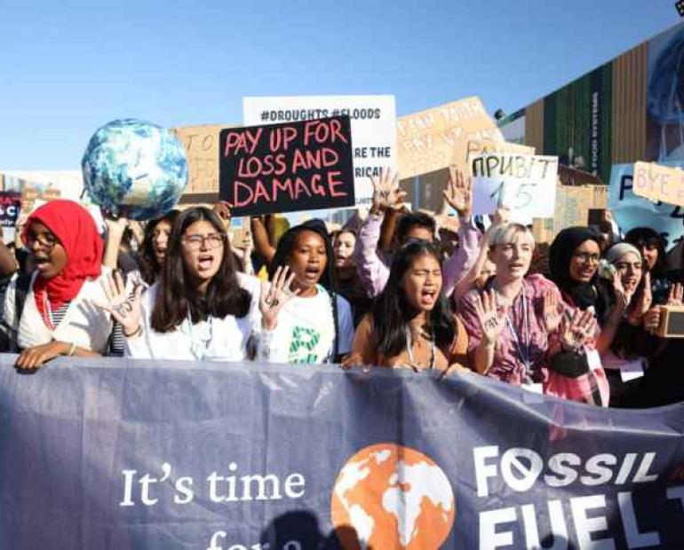 Young people demonstrate, holding placards about climate change.