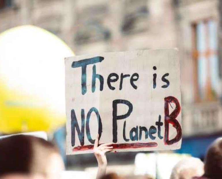 A hand holds a placard that reads "There is NO planet B"