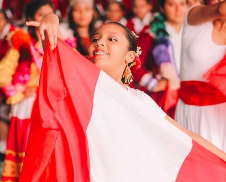 Foto de una niña sonriendo con la bandera del Perú. 