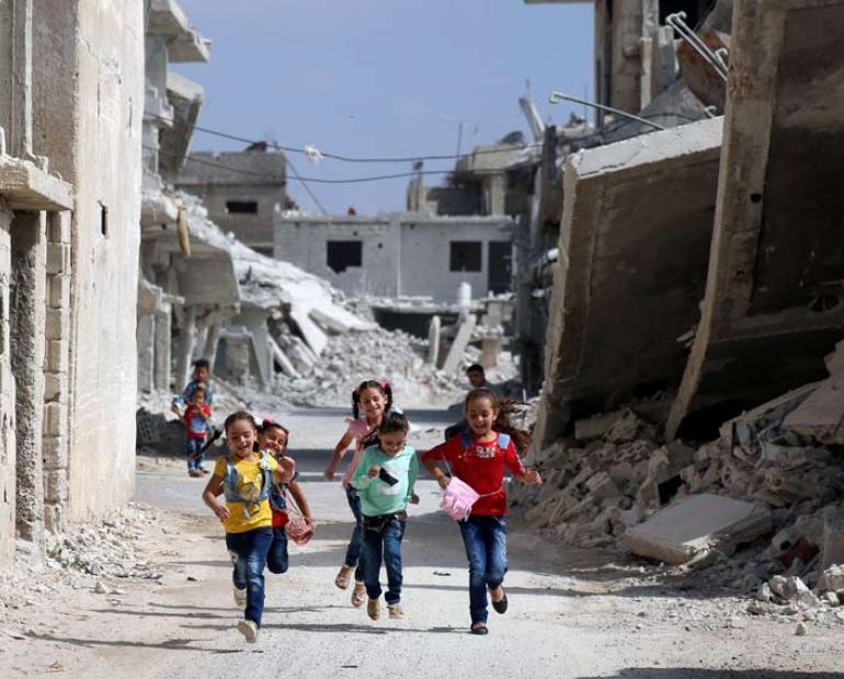 Children running amid a war destructed street