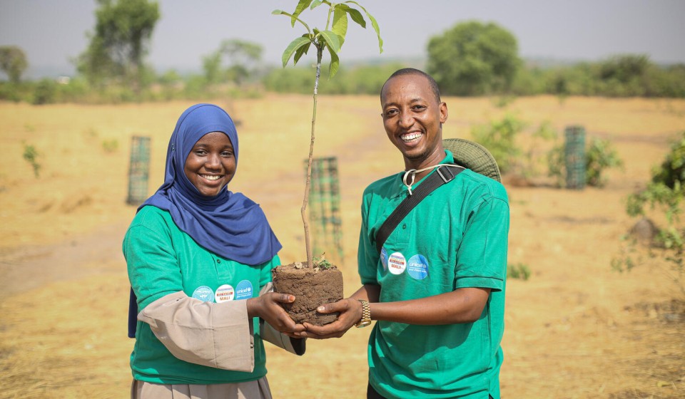 Two young people holding a sapling