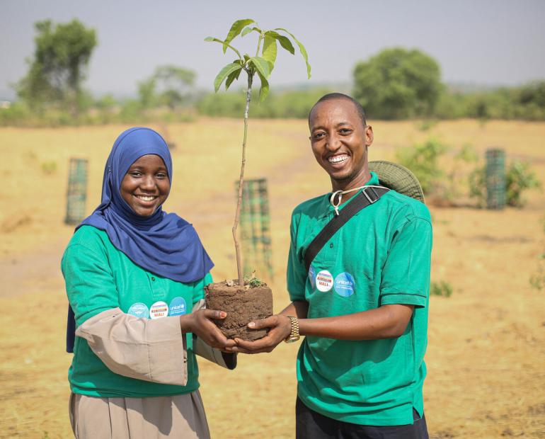 Two young people holding a sapling
