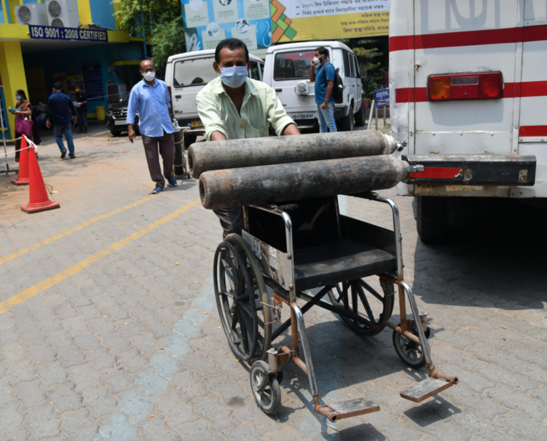 A health worker carries Oxygen cylinder on a wheel chair at MMC Covid hospital in Guwahati on April 30, 2021. 